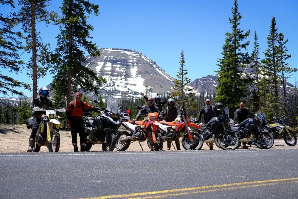 SOAF riders with their motorcycles in front of a mountain peak